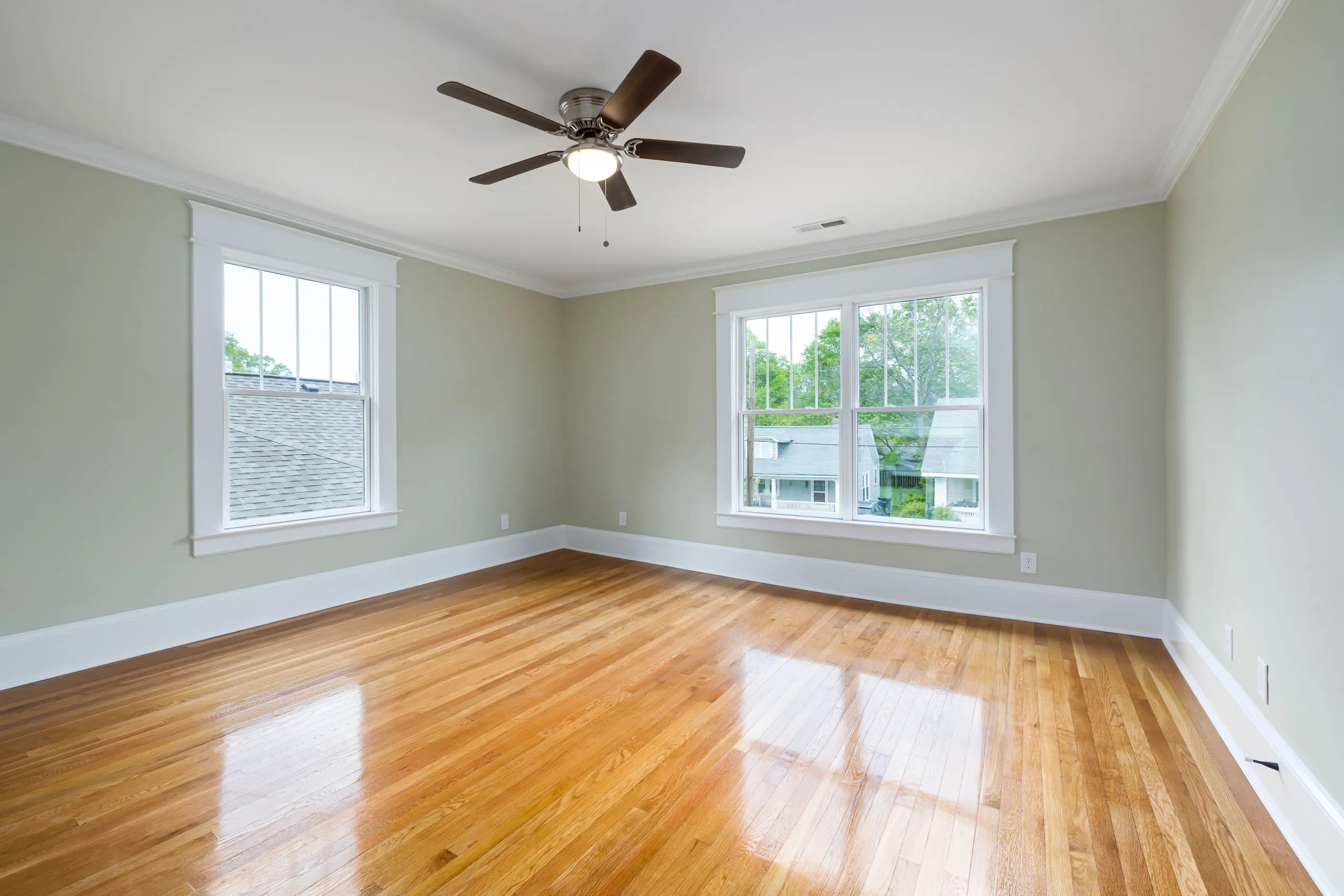 A bright, freshly cleaned empty room with hardwood floors, ready for its next occupant